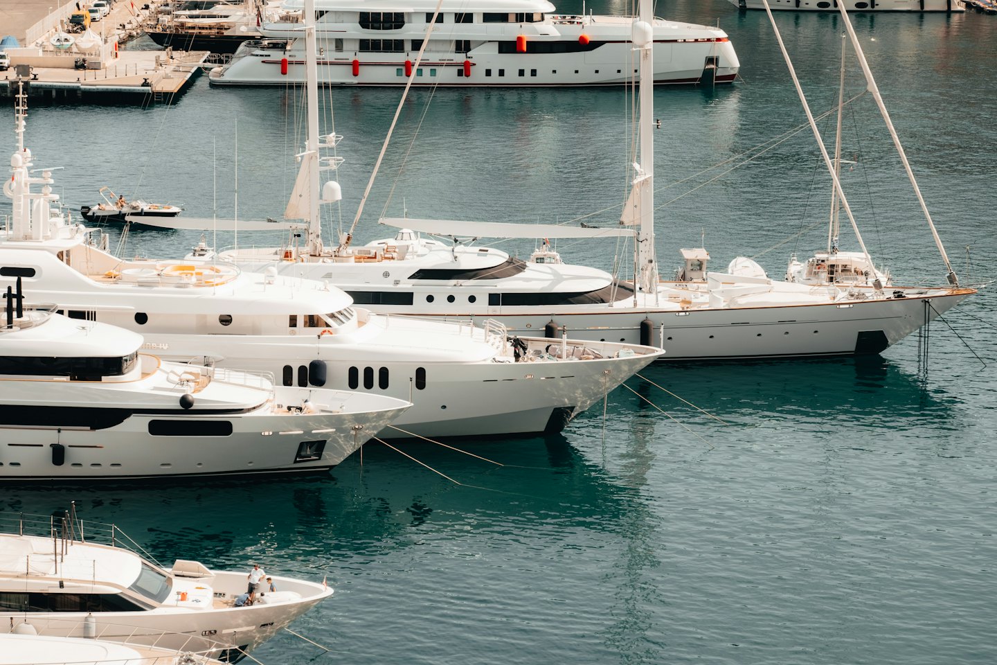 Luxury yachts and sailboats moored together in a bustling marina.